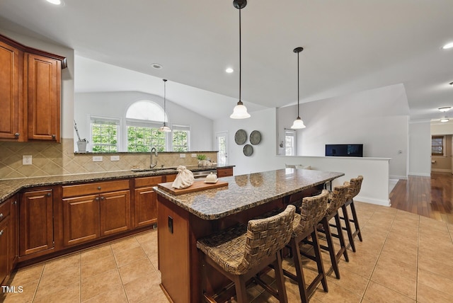 kitchen with decorative backsplash, lofted ceiling, light tile patterned floors, and a breakfast bar