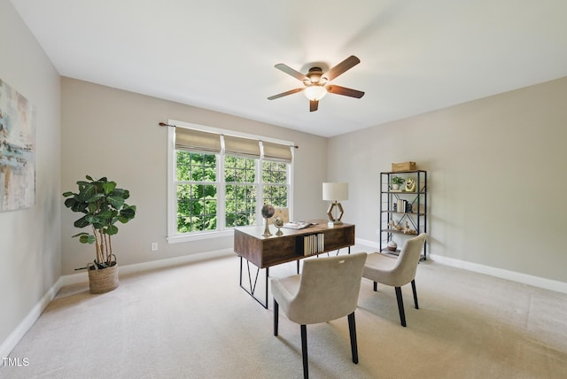 office space with baseboards, a ceiling fan, and light carpet