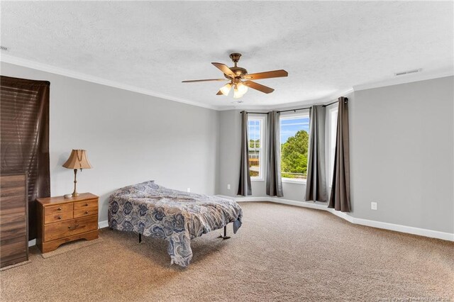 carpeted bedroom with crown molding, visible vents, baseboards, ceiling fan, and a textured ceiling