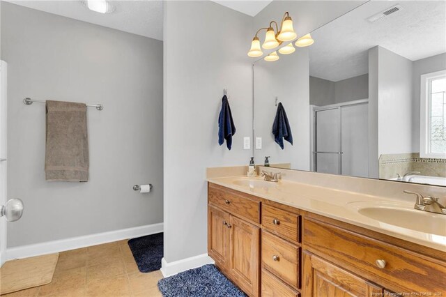 full bath featuring visible vents, double vanity, baseboards, a sink, and a stall shower