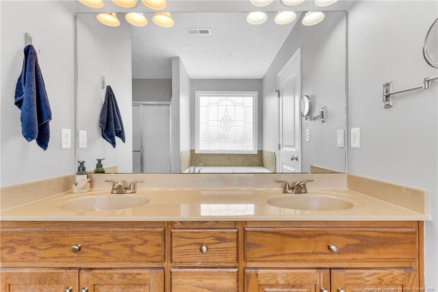 bathroom featuring a sink, a garden tub, double vanity, and visible vents