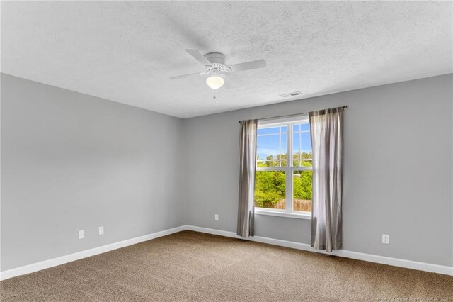 carpeted empty room with a ceiling fan, baseboards, visible vents, and a textured ceiling
