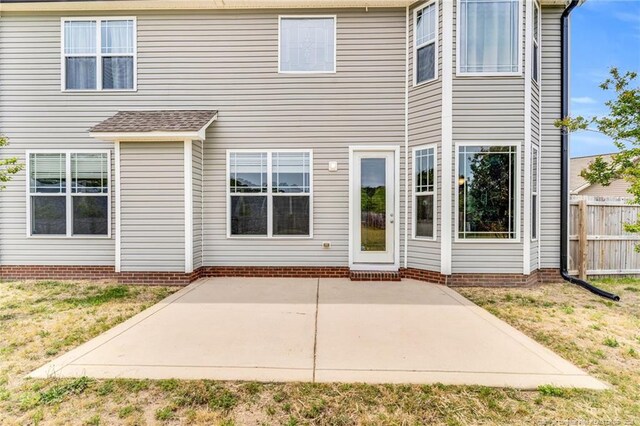 back of property with fence, a yard, and a patio area