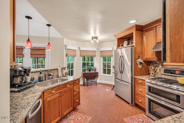 11 Bridgeport Dr, Durham, NC 27713 - kitchen featuring appliances with stainless steel finishes, brown cabinets, a sink, brick floor, and under cabinet range hood