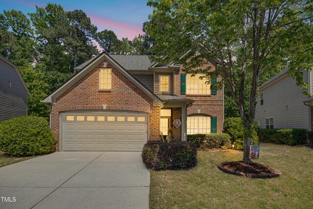 traditional-style home with roof with shingles, brick siding, a garage, concrete driveway, and a lawn