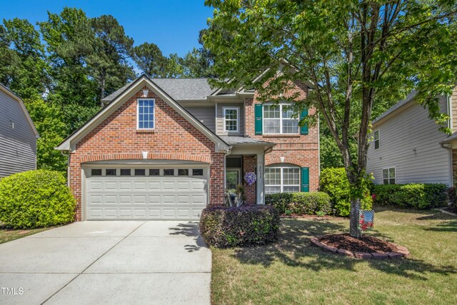 traditional-style house with an attached garage, driveway, a front lawn, and brick siding