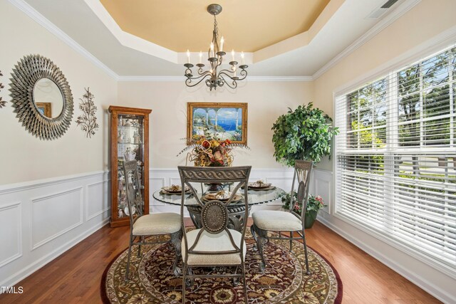 dining room featuring visible vents, a notable chandelier, wood finished floors, and a raised ceiling