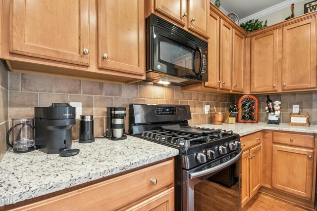 kitchen with crown molding, black microwave, light stone counters, stainless steel range with gas cooktop, and tasteful backsplash