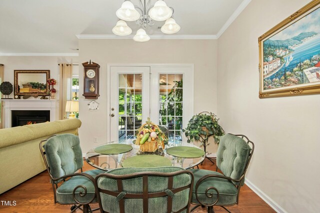 dining area with crown molding, a chandelier, french doors, wood finished floors, and a lit fireplace
