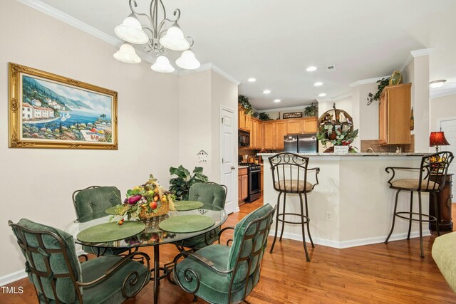 dining space with crown molding, an inviting chandelier, and light wood-style flooring