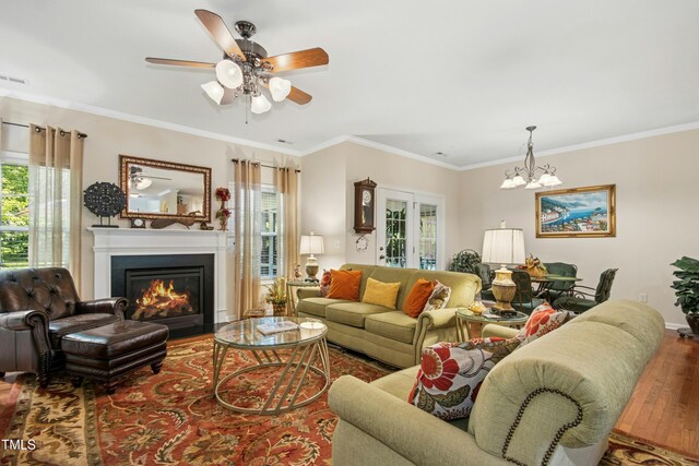 living room featuring a fireplace with flush hearth, wood finished floors, a wealth of natural light, and ornamental molding