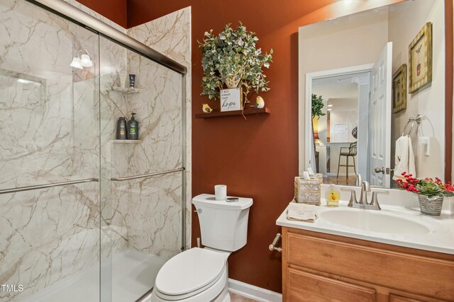 full bath featuring a marble finish shower, baseboards, vanity, and toilet