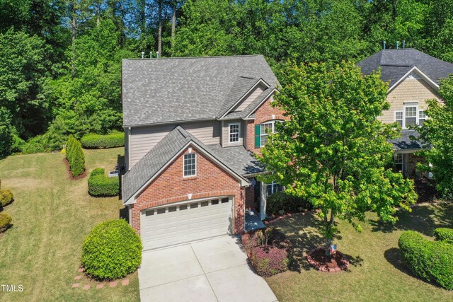 view of front of home with brick siding, a shingled roof, a front lawn, and driveway