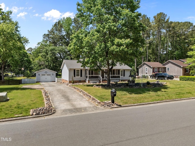 view of front facade with fence, aphalt driveway, a detached garage, an outbuilding, and covered porch
