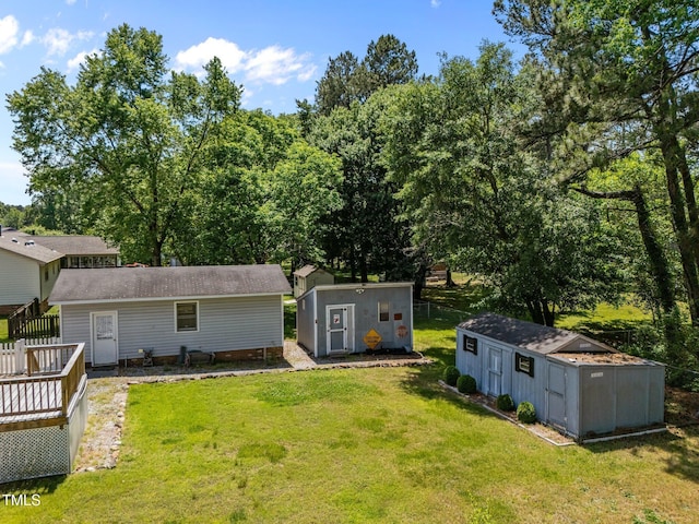 rear view of property with a lawn, a storage unit, an outbuilding, and a wooden deck
