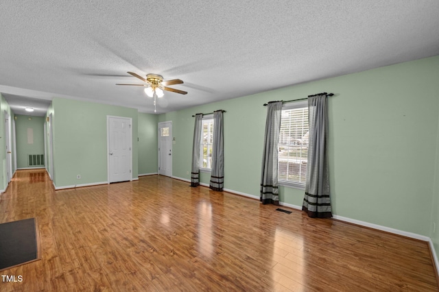 spare room with a ceiling fan, a textured ceiling, visible vents, and wood finished floors