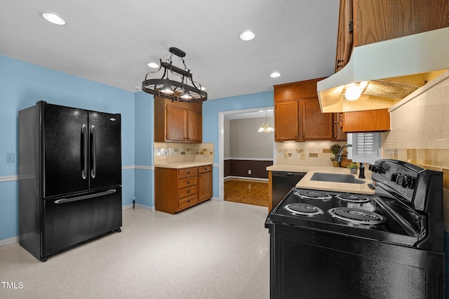 kitchen featuring brown cabinetry, backsplash, a sink, black appliances, and recessed lighting