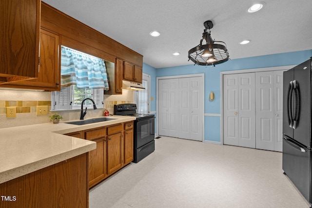 kitchen with a sink, under cabinet range hood, black appliances, and brown cabinets