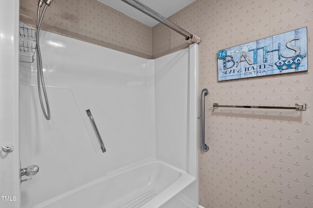 bathroom featuring a textured ceiling, wallpapered walls, and  shower combination