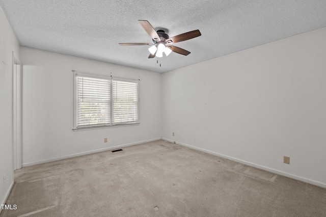 carpeted spare room with baseboards, a ceiling fan, a textured ceiling, and visible vents