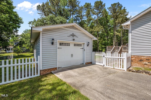 detached garage featuring aphalt driveway and fence