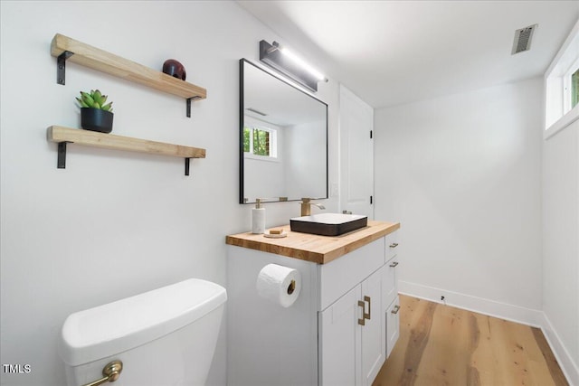 2904 Sprucewood Dr, Durham, NC 27707 - half bath featuring visible vents, vanity, wood finished floors, toilet, and baseboards