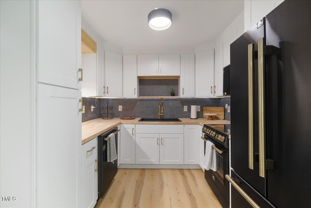 2904 Sprucewood Dr, Durham, NC 27707 - kitchen featuring light wood-type flooring, a sink, black appliances, wood counters, and white cabinetry