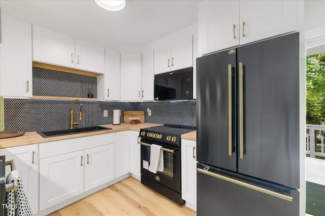 2904 Sprucewood Dr, Durham, NC 27707 - kitchen with a sink, black appliances, light wood finished floors, and white cabinetry