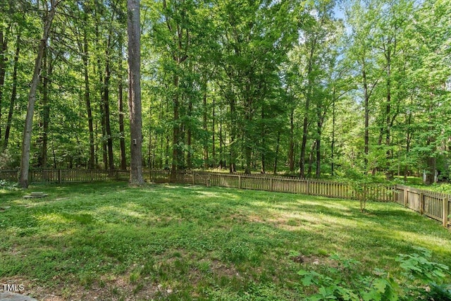 view of yard featuring a fenced backyard and a forest view