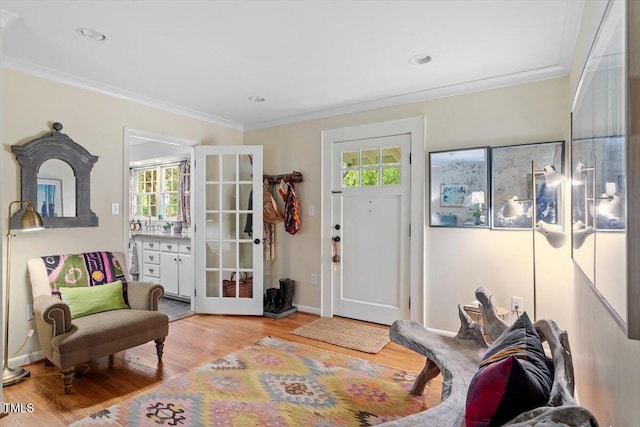 entryway with baseboards, ornamental molding, a wealth of natural light, and light wood-type flooring
