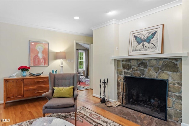 living area featuring baseboards, ornamental molding, wood finished floors, and a fireplace