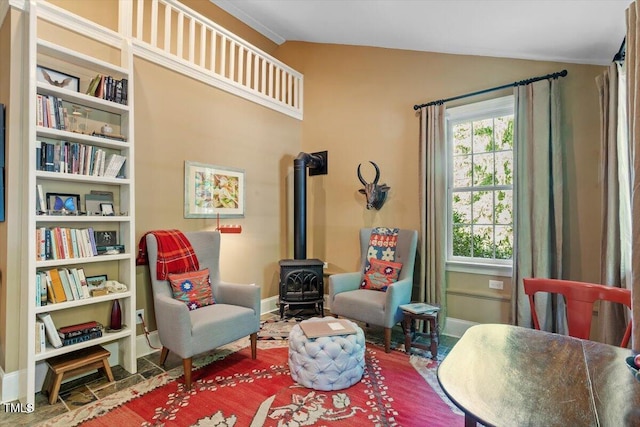 living area with baseboards, a wood stove, and vaulted ceiling