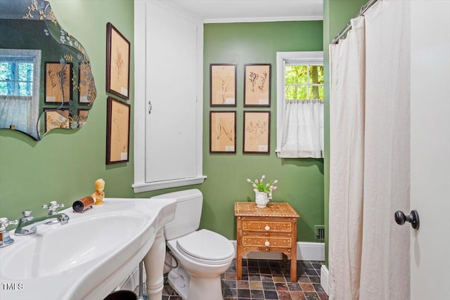 full bathroom featuring toilet, a shower with curtain, stone finish floor, and a sink