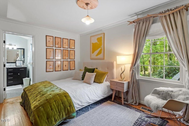 bedroom featuring visible vents, ornamental molding, wood finished floors, and ensuite bathroom