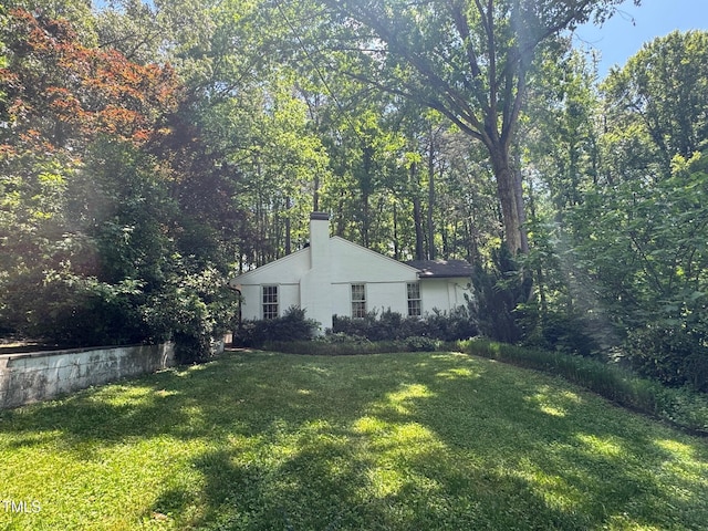 view of side of property featuring a chimney, a yard, and stucco siding