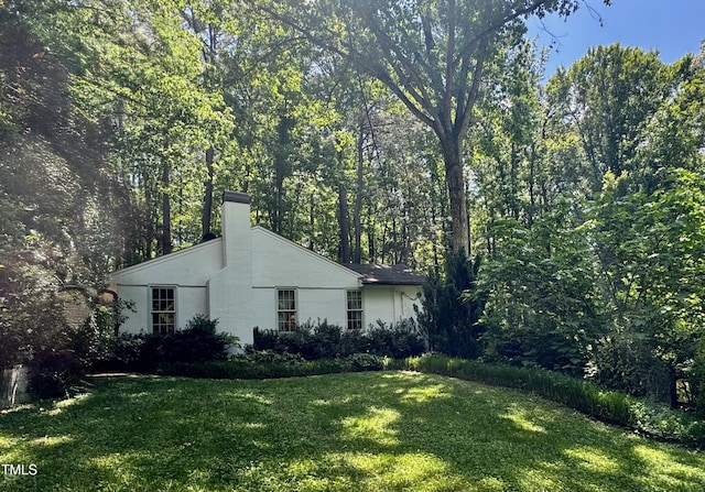 view of property exterior featuring a lawn, a chimney, and stucco siding
