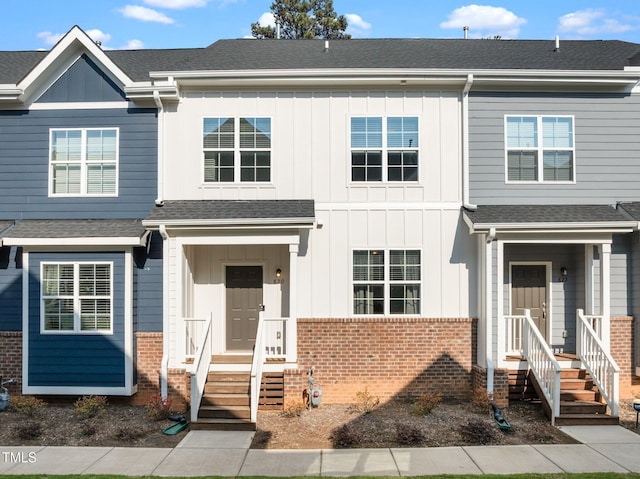 view of front of property featuring a shingled roof, board and batten siding, and brick siding
