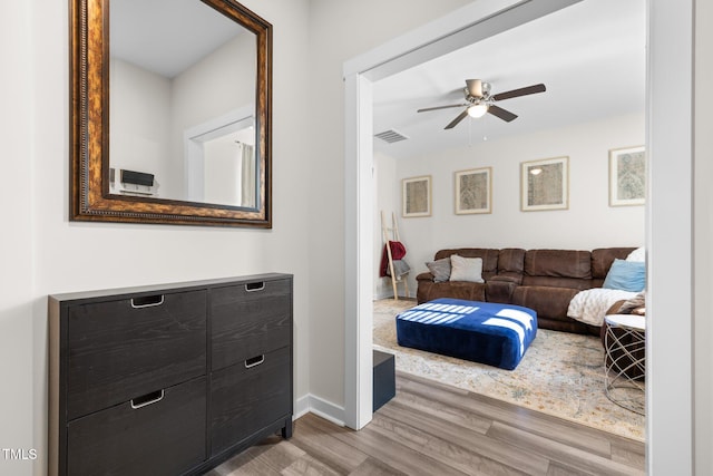 interior space featuring a ceiling fan, baseboards, visible vents, and wood finished floors