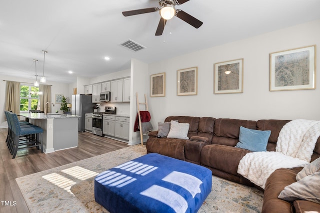 living room with ceiling fan, recessed lighting, wood finished floors, and visible vents