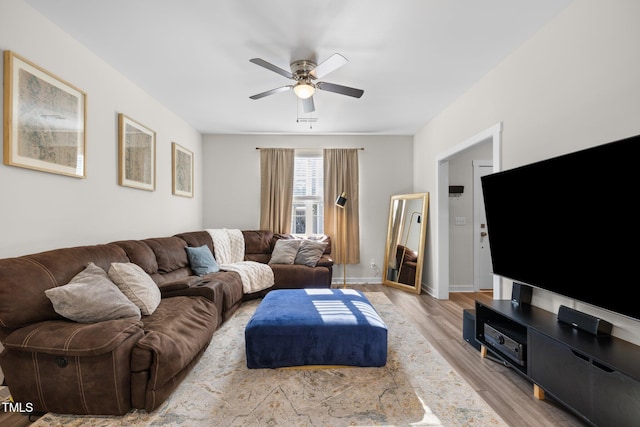 living room with a ceiling fan, baseboards, and light wood-style flooring