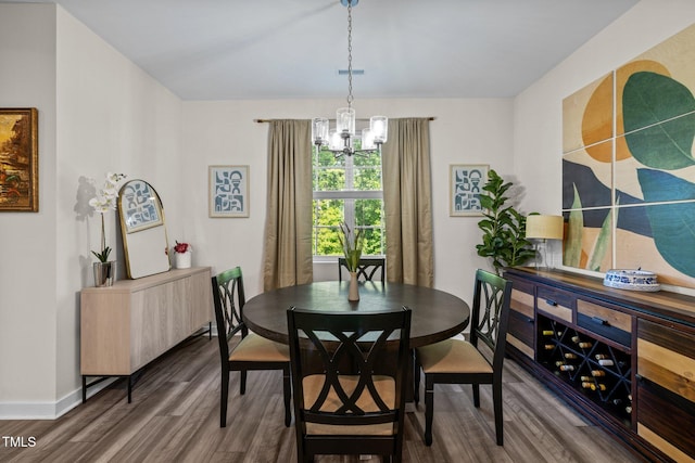 dining space with baseboards, a chandelier, and wood finished floors