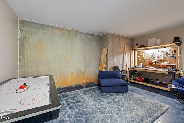 rec room with a workshop area and unfinished concrete flooring