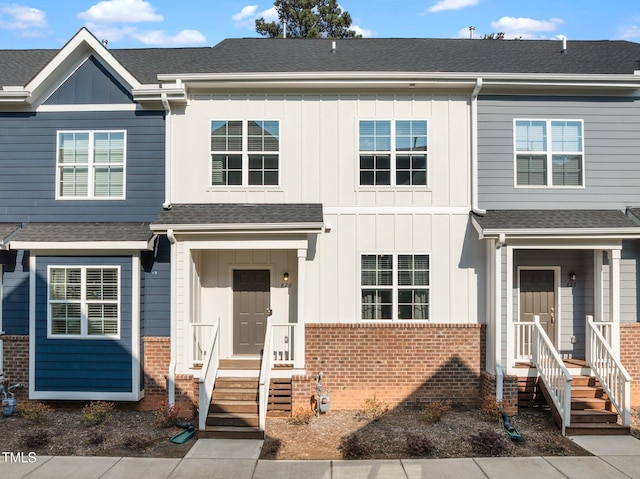 multi unit property featuring a shingled roof, board and batten siding, and brick siding