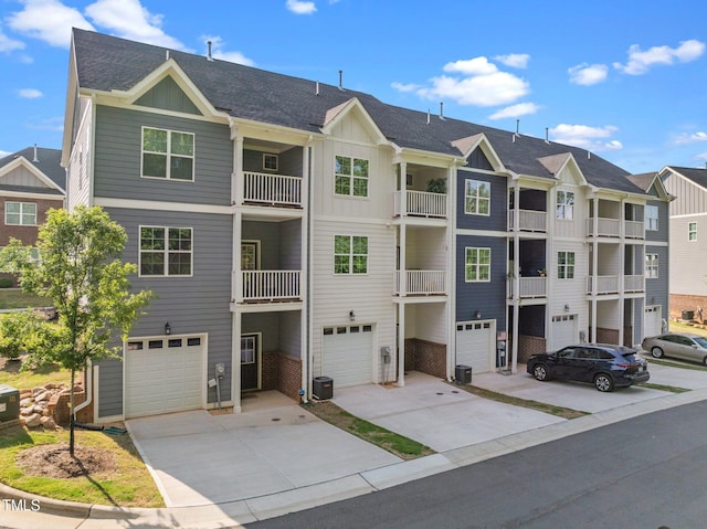 view of property with central air condition unit, an attached garage, driveway, and a residential view