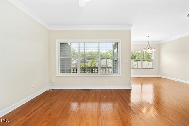 unfurnished room with crown molding, baseboards, hardwood / wood-style flooring, and a chandelier