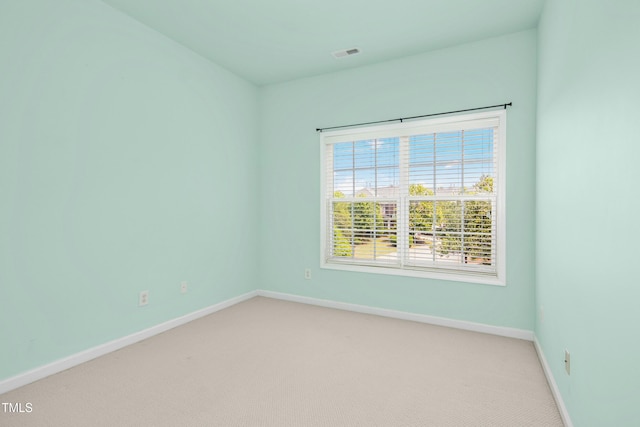 empty room with baseboards, light carpet, and visible vents