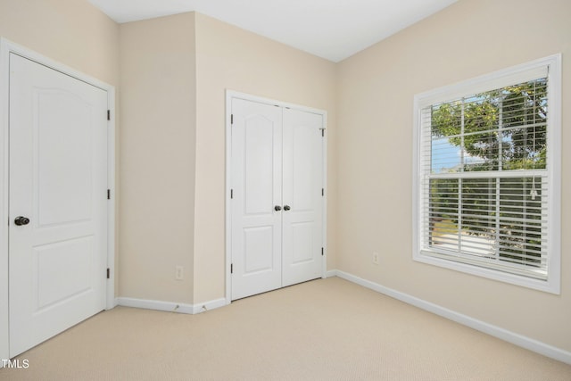 unfurnished bedroom featuring baseboards, carpet, and a closet