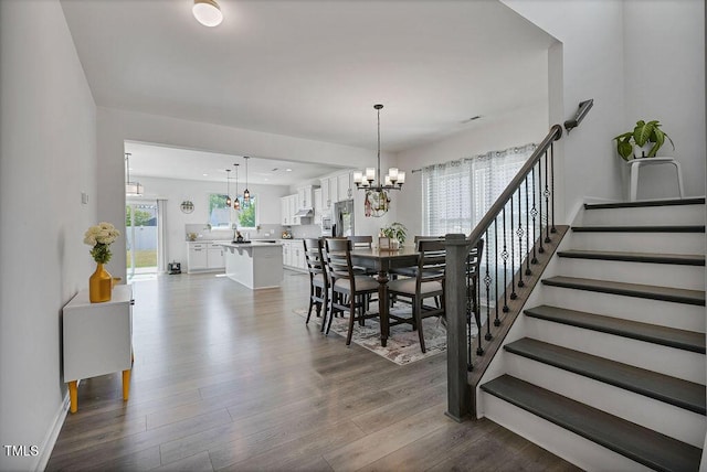 dining area featuring a chandelier, dark wood-type flooring, stairway, and baseboards