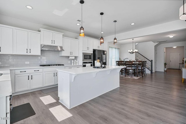 kitchen featuring black appliances, under cabinet range hood, light countertops, recessed lighting, and backsplash
