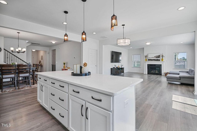 kitchen with a chandelier, light wood-type flooring, a center island, light countertops, and white cabinets